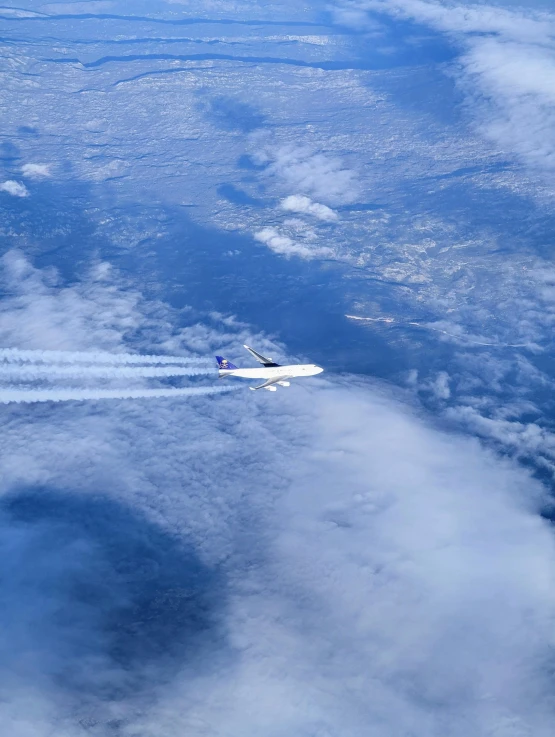 a plane flies over the clouds in the blue sky