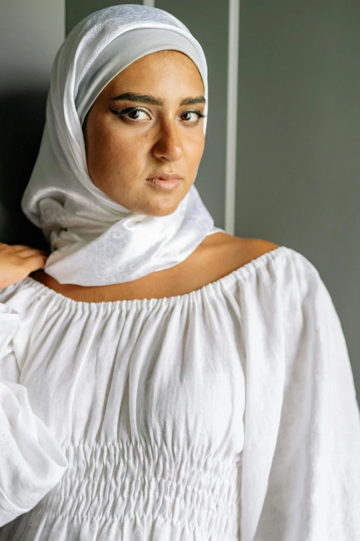 a woman with a headscarf is leaning on a wall