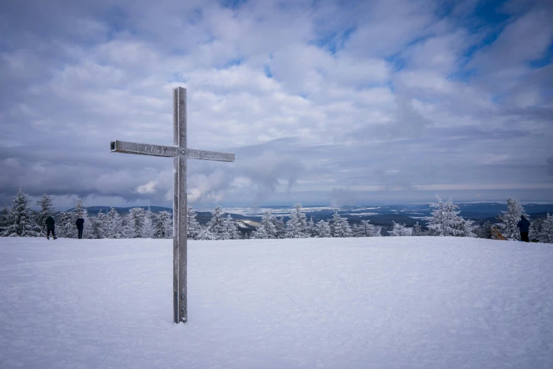 a cross on the top of a snow covered slope