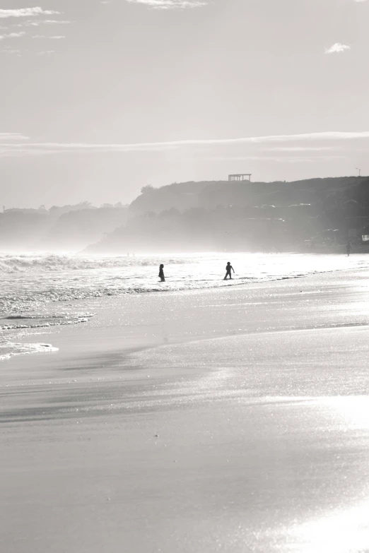 two people walking on the beach near the ocean