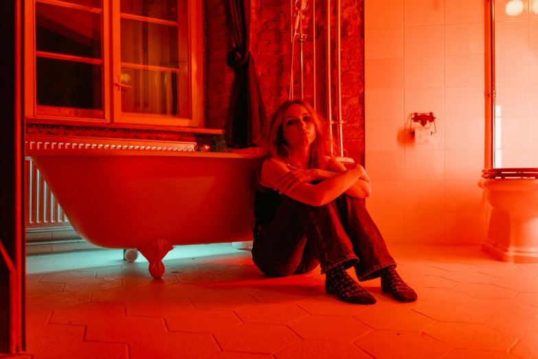 woman sitting on bathtub in bathroom with tub, windows and lighting