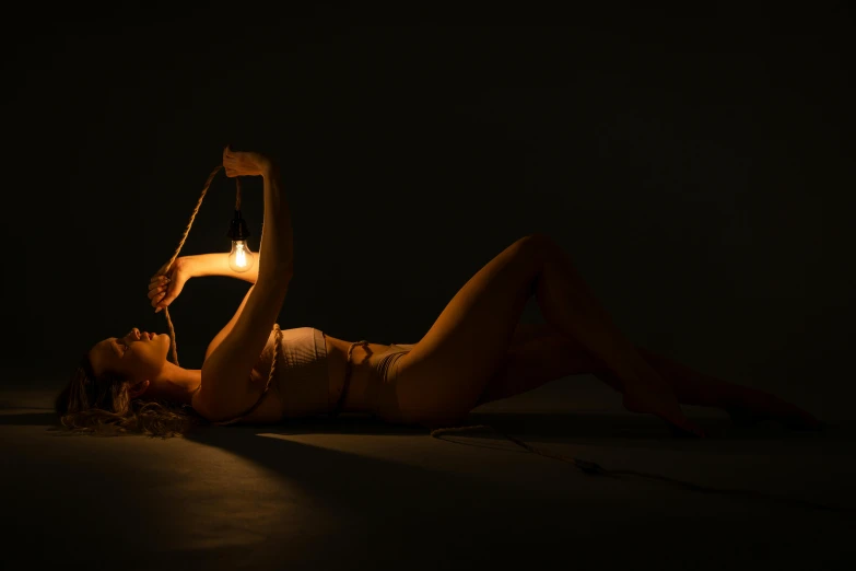 a woman laying on the ground with an electric light in her hand