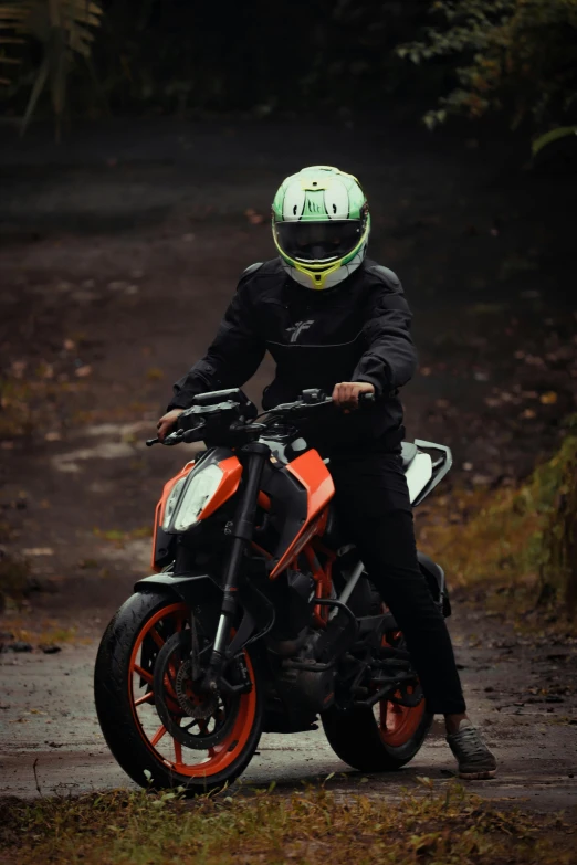 a man in black riding on the back of an orange motorcycle