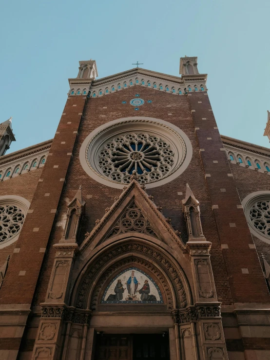 the front side of a brown church with two clocks on it