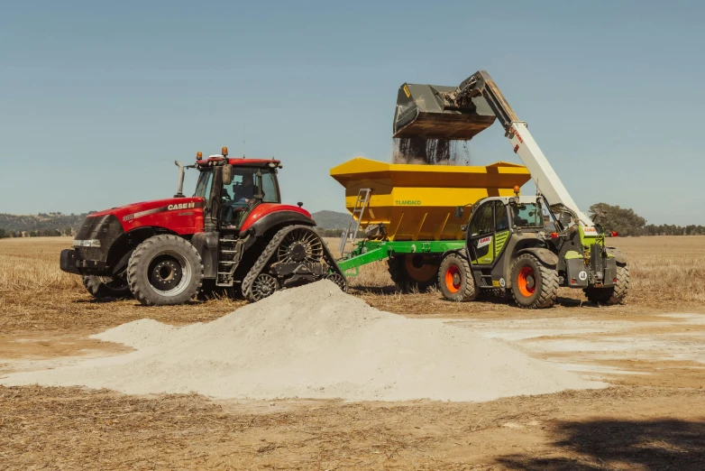 two farm tractors are parked in a dirt field