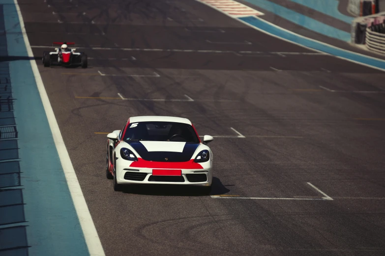 two cars on a race track, with one car facing forward