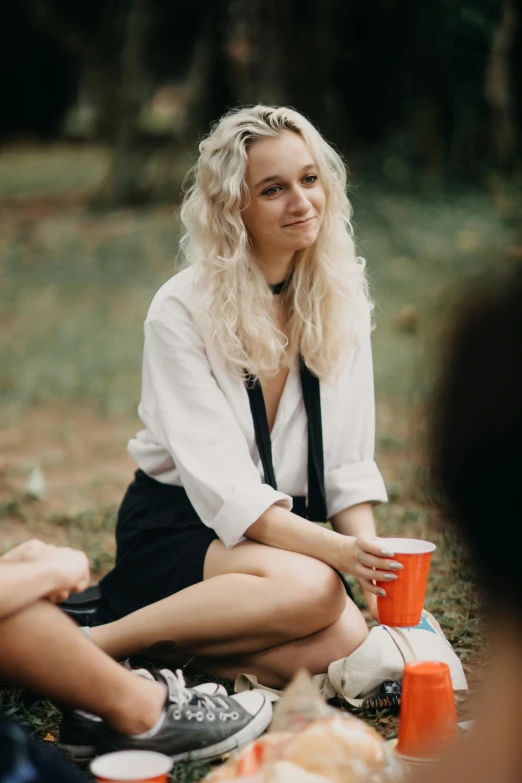 a girl sitting on a grass covered field with food