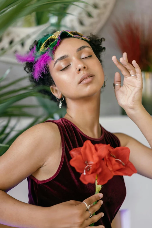 a woman standing in front of some plants while holding a flower