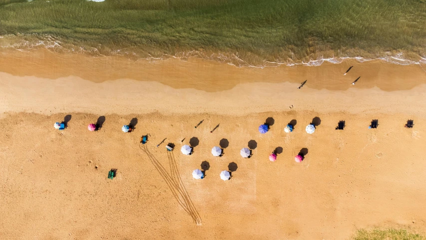 overhead view of a sandy beach with a group of people holding umbrellas