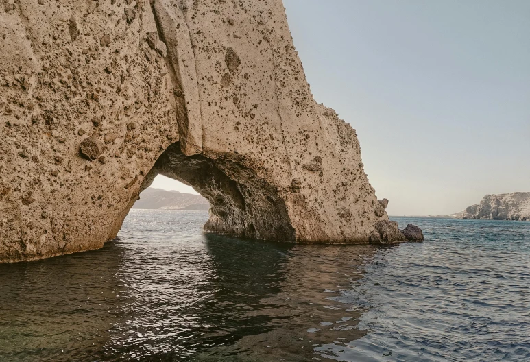 a closeup of an arch shaped rocky wall in the water