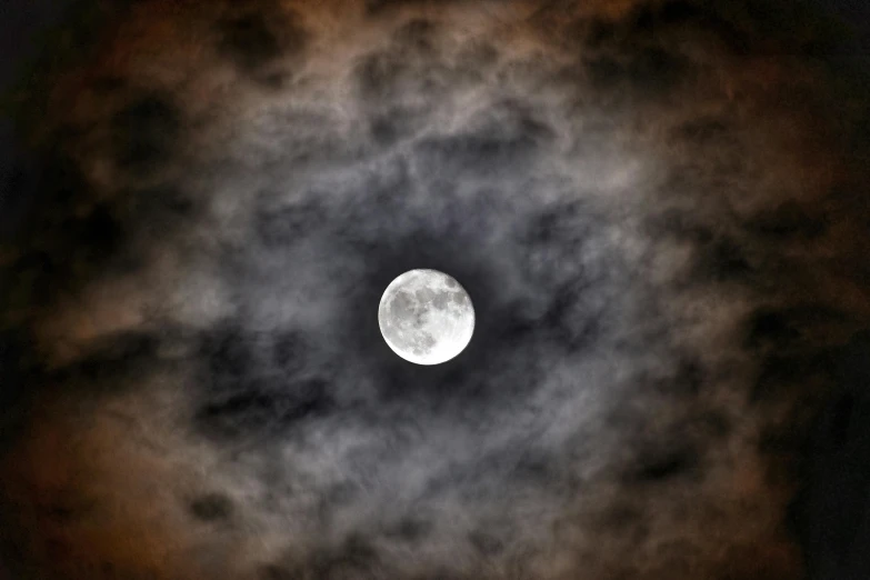 the full moon is lit up as it passes through the clouds
