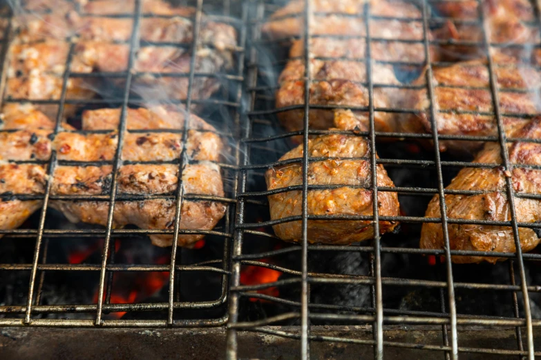 several grilled meats on the grill, with smoke coming out