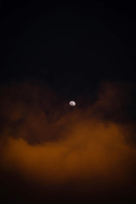 the moon is visible in a dark cloud covered sky