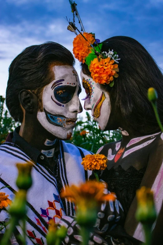 two people with face makeup kissing while wearing floral crowns