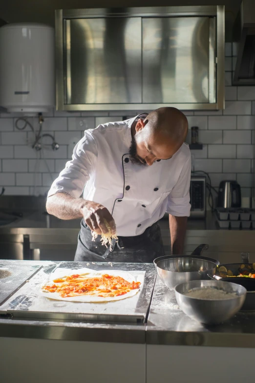 a man wearing a chef outfit making a pizza