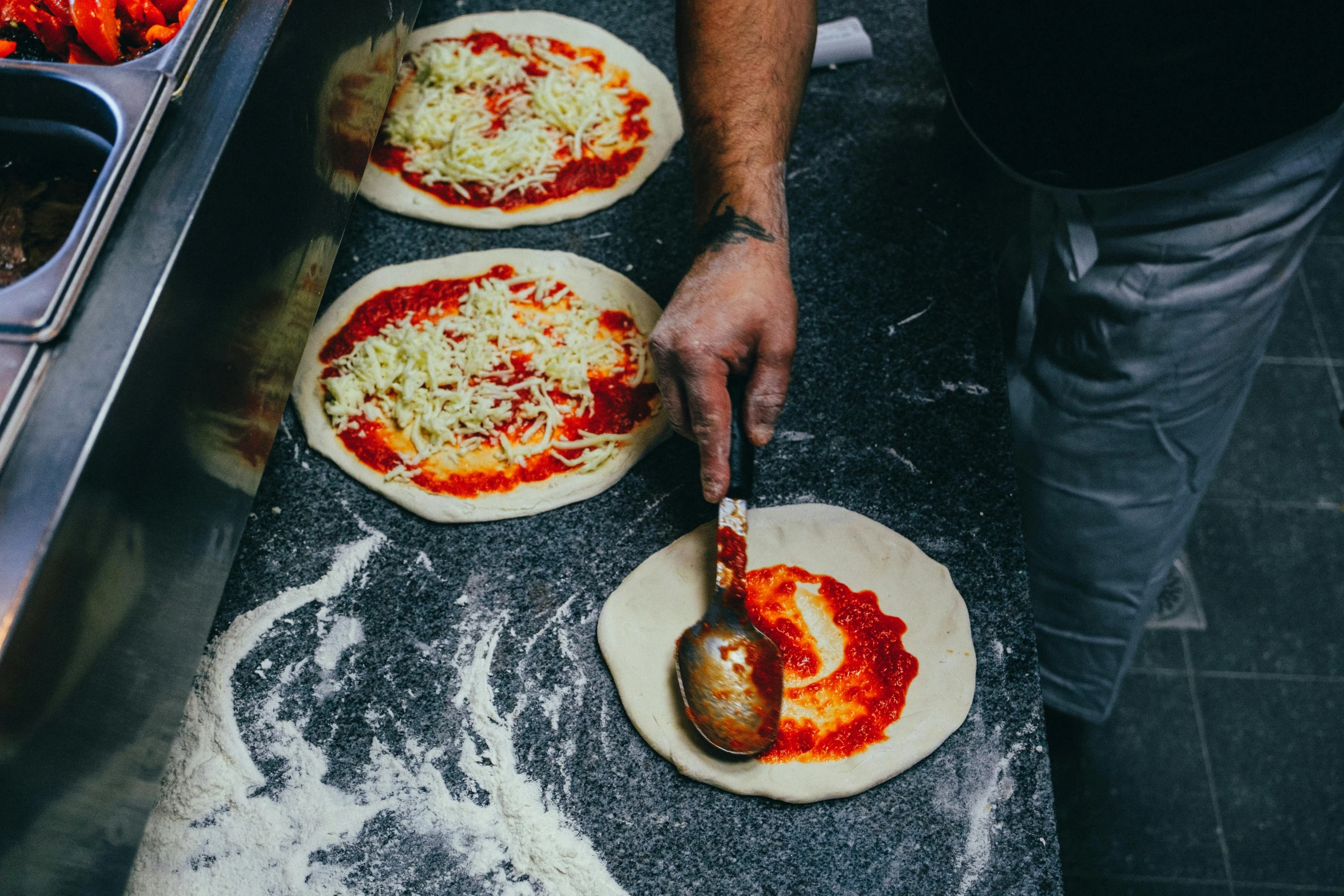 someone in an oven making pizzas on wooden pizza paddles