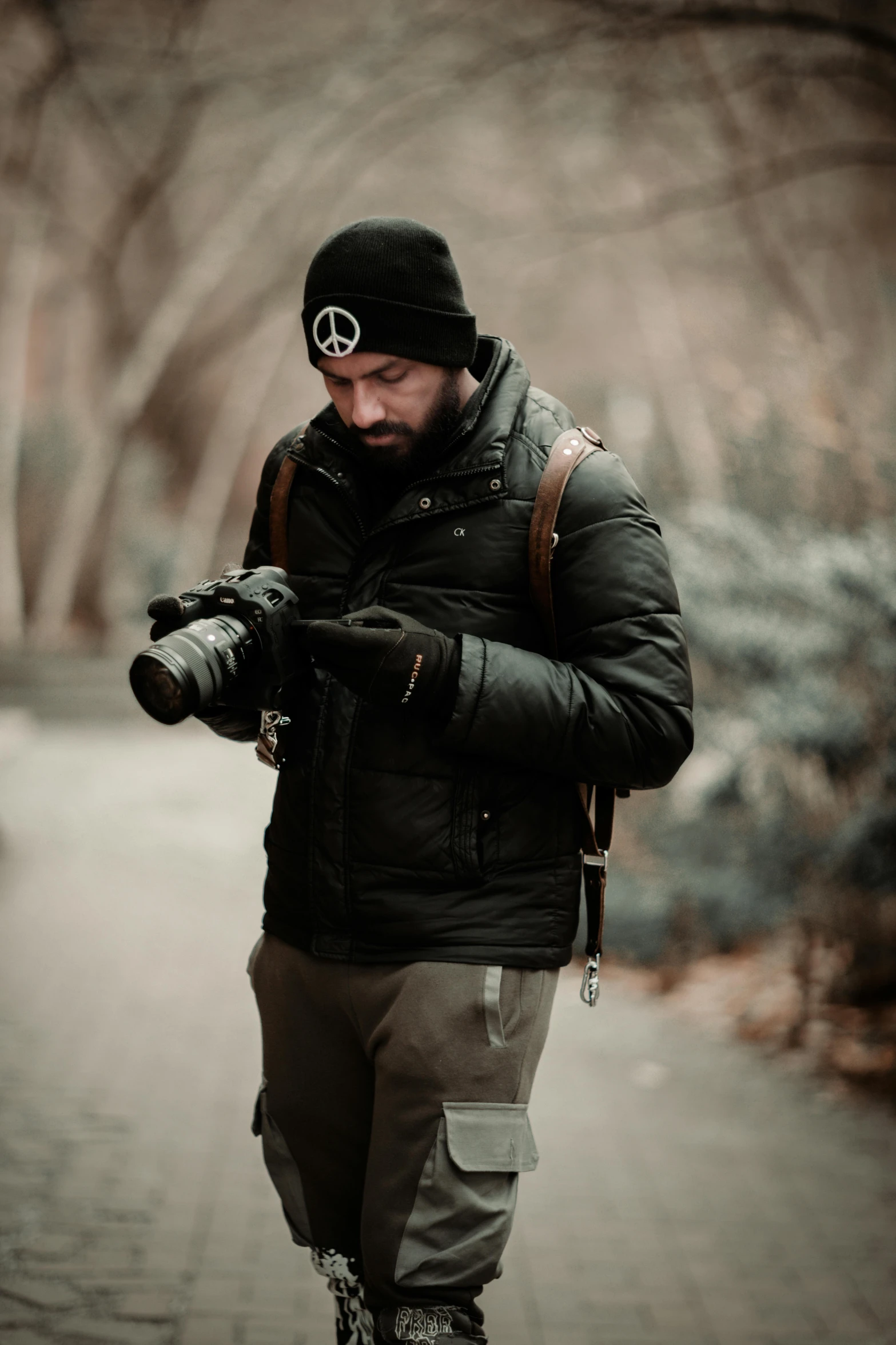 a man wearing a backpack and a beanie, standing on the sidewalk with his camera in hand