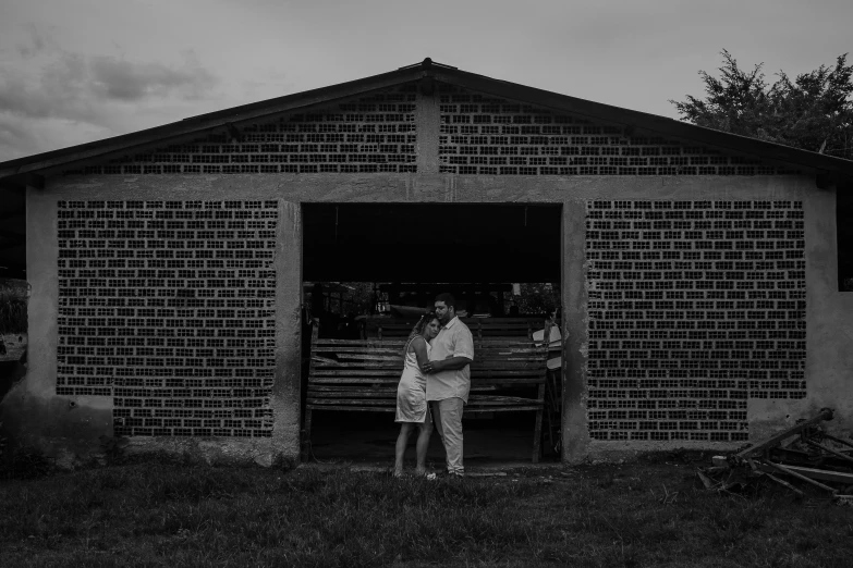 a couple standing in front of a barn