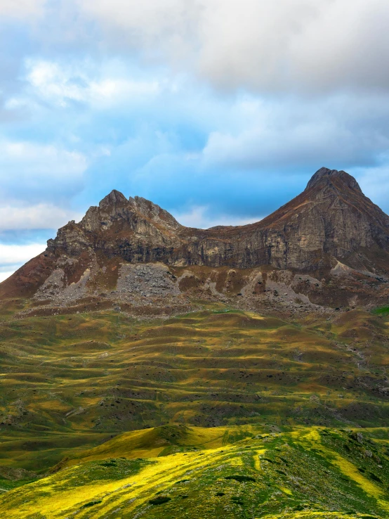 two very large mountains towering over a grassy hillside