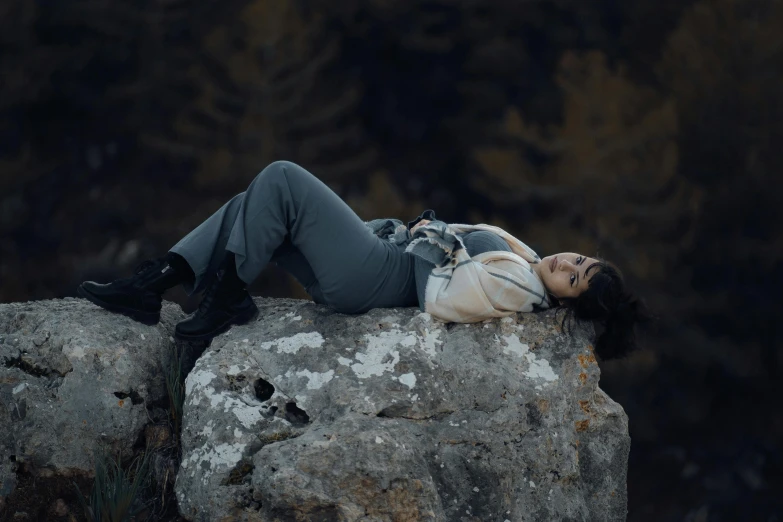 a woman laying down on top of a large rock