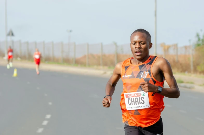 a male athlete running in an orange shirt