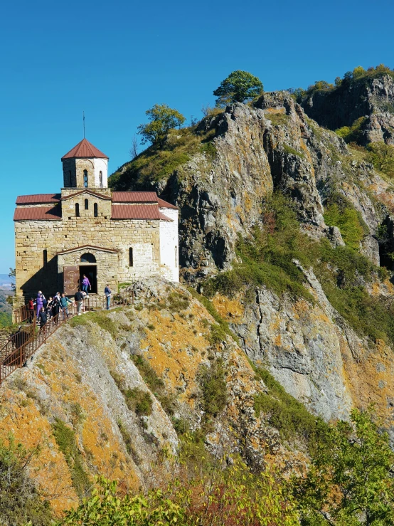 people walk down a steep hill next to a large building