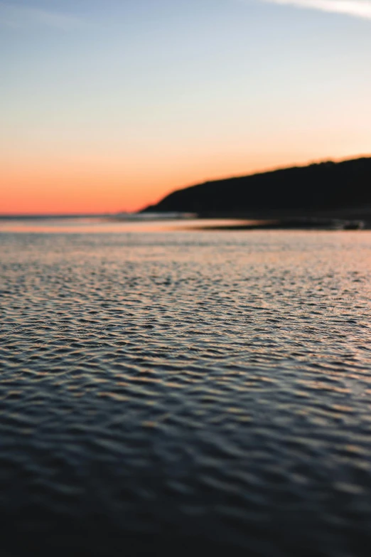 calm water at sunset with a mountain in the background