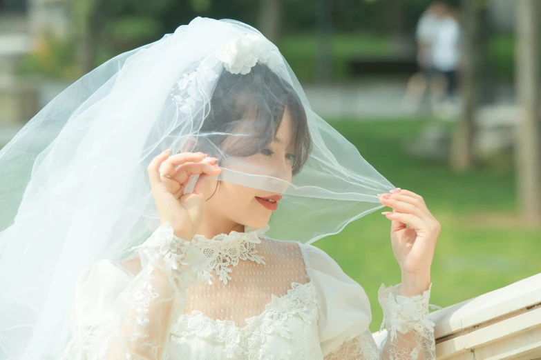 the bride with veil over her head looks to the side