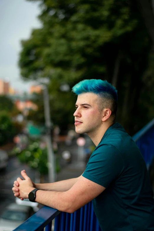 a young man with blue hair standing on the side of a street