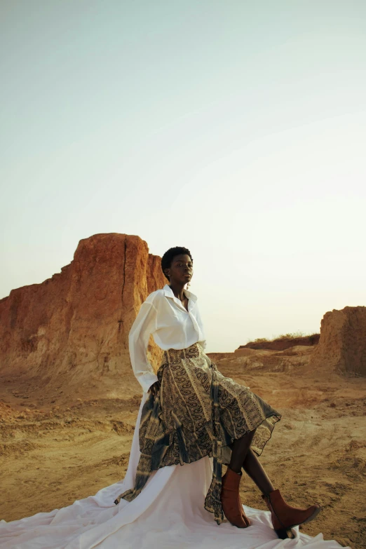 a woman in a dress sits on a rock