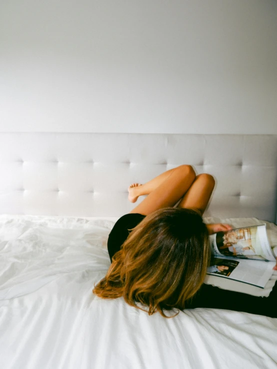 a woman is laying on her stomach with her feet resting on the bed