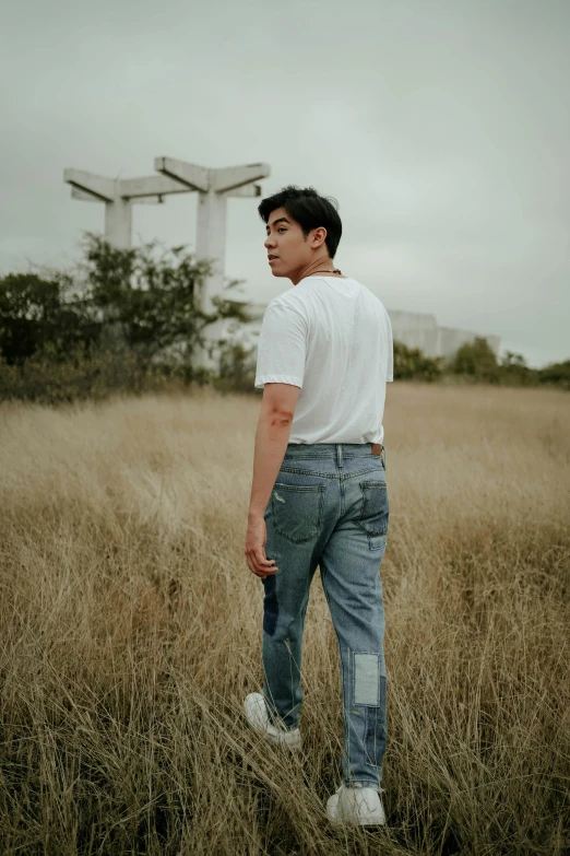 man standing in a field looking back with a tower behind him