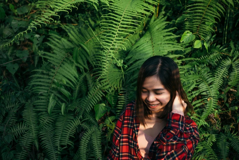 a woman with long hair smiles while standing among ferns