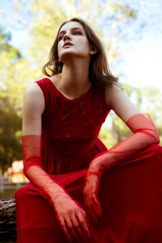 a woman in red is sitting on a log