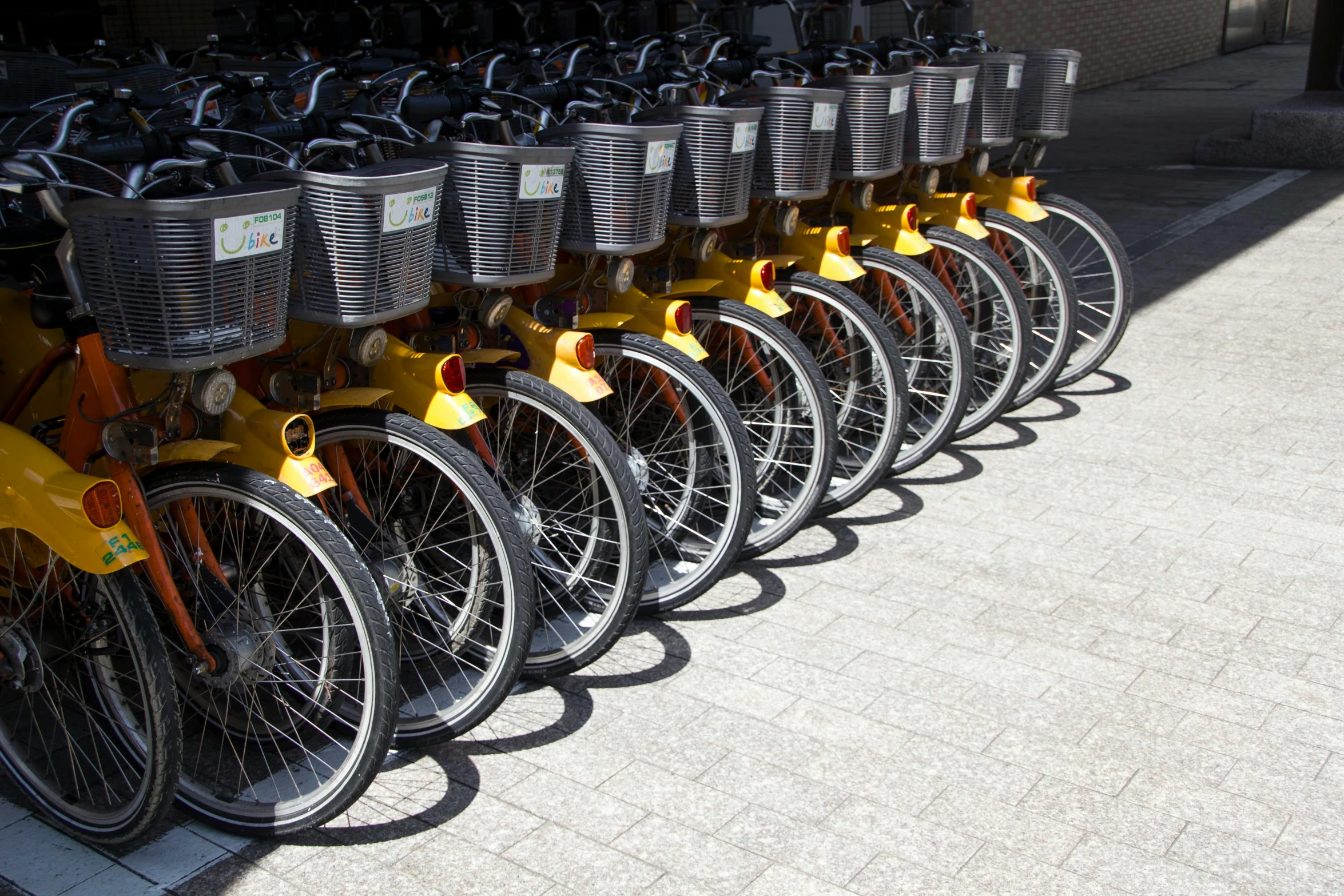 the yellow and black bicycles are lined up on the sidewalk