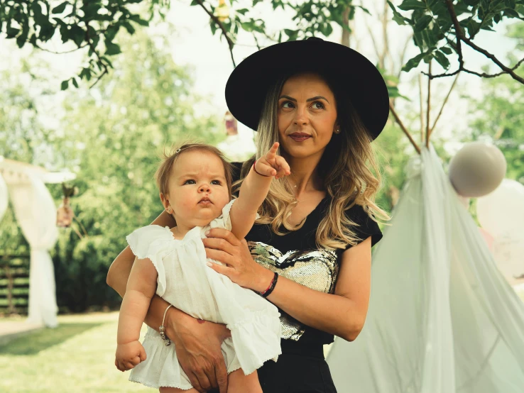 a woman holding a baby girl under a tree