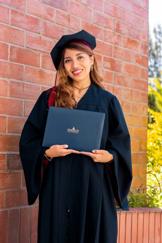 young woman in graduation gown holding her diploma