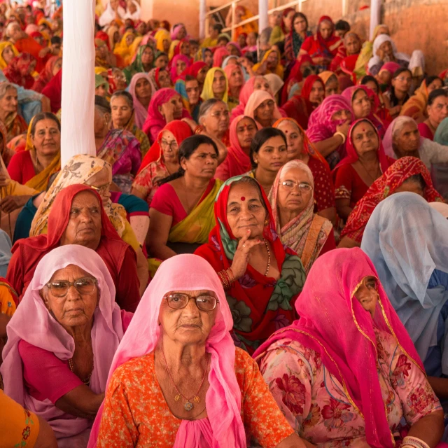 many women sitting in a line with one holding her hand up