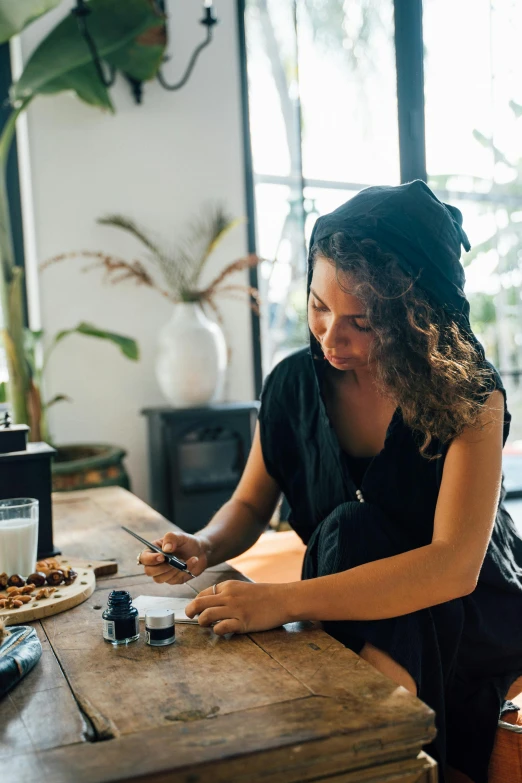 a woman sits at a table, working on her phone