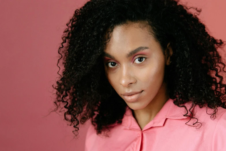 a woman in pink shirt with curly hair and pink eyes