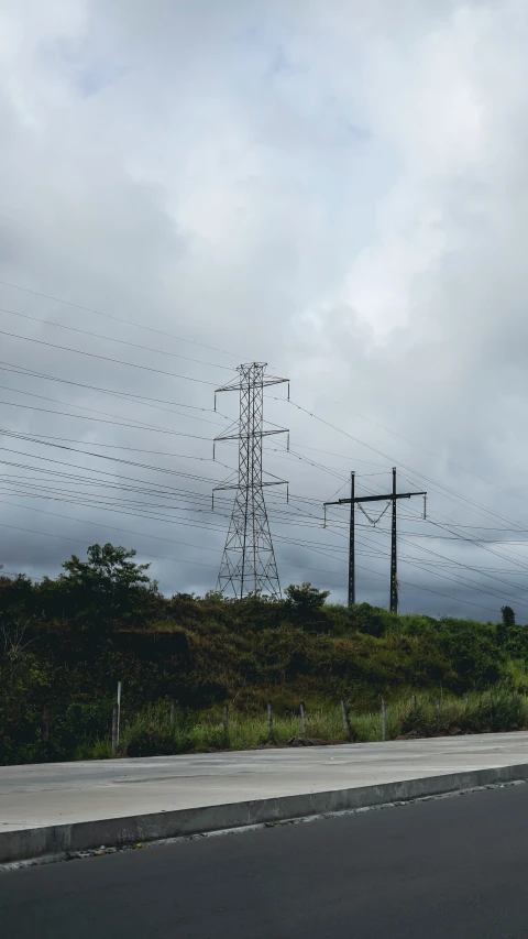 power lines crossing across the road in the midst of cloudy skies