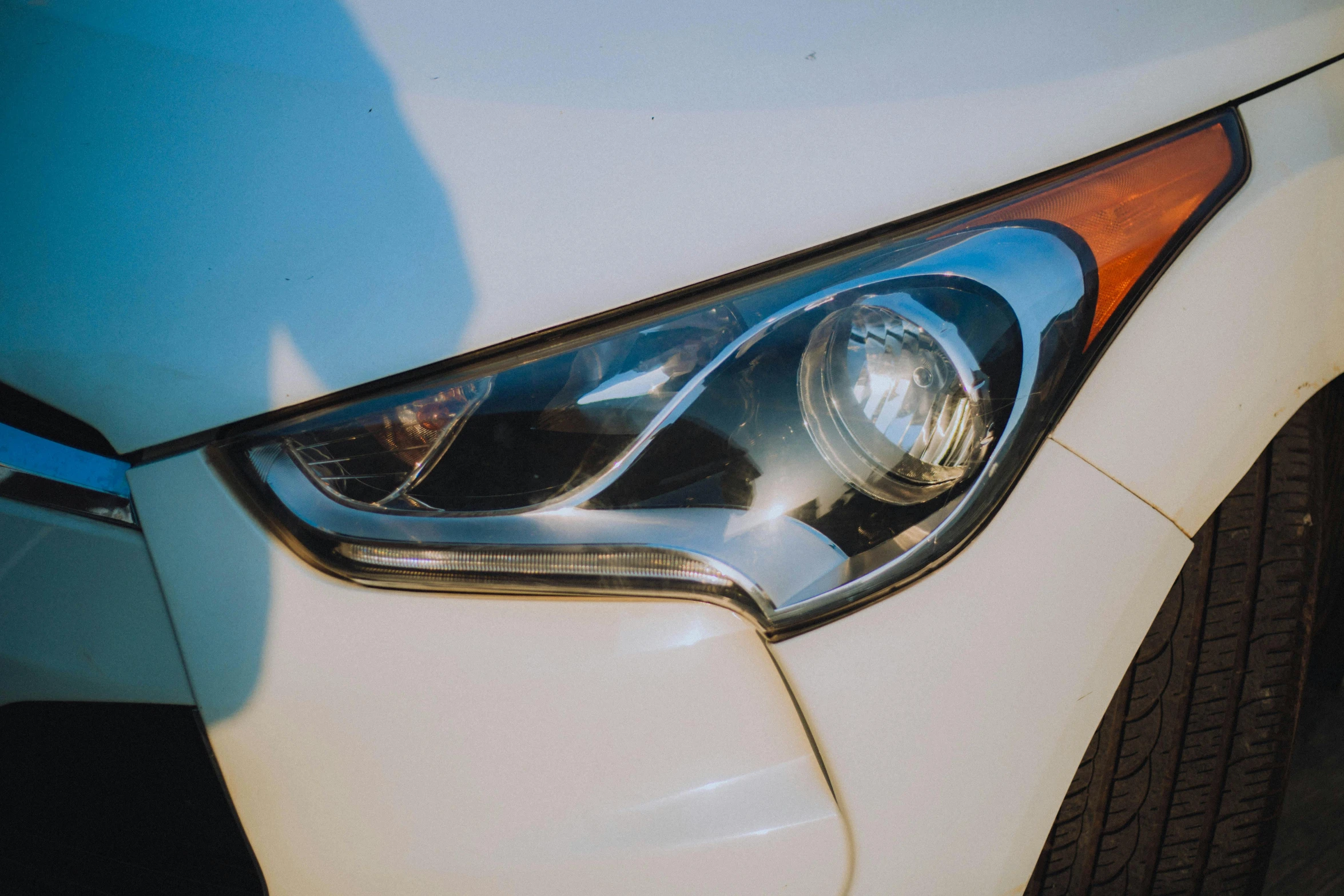 the lights of an automobile are seen against the side of the vehicle