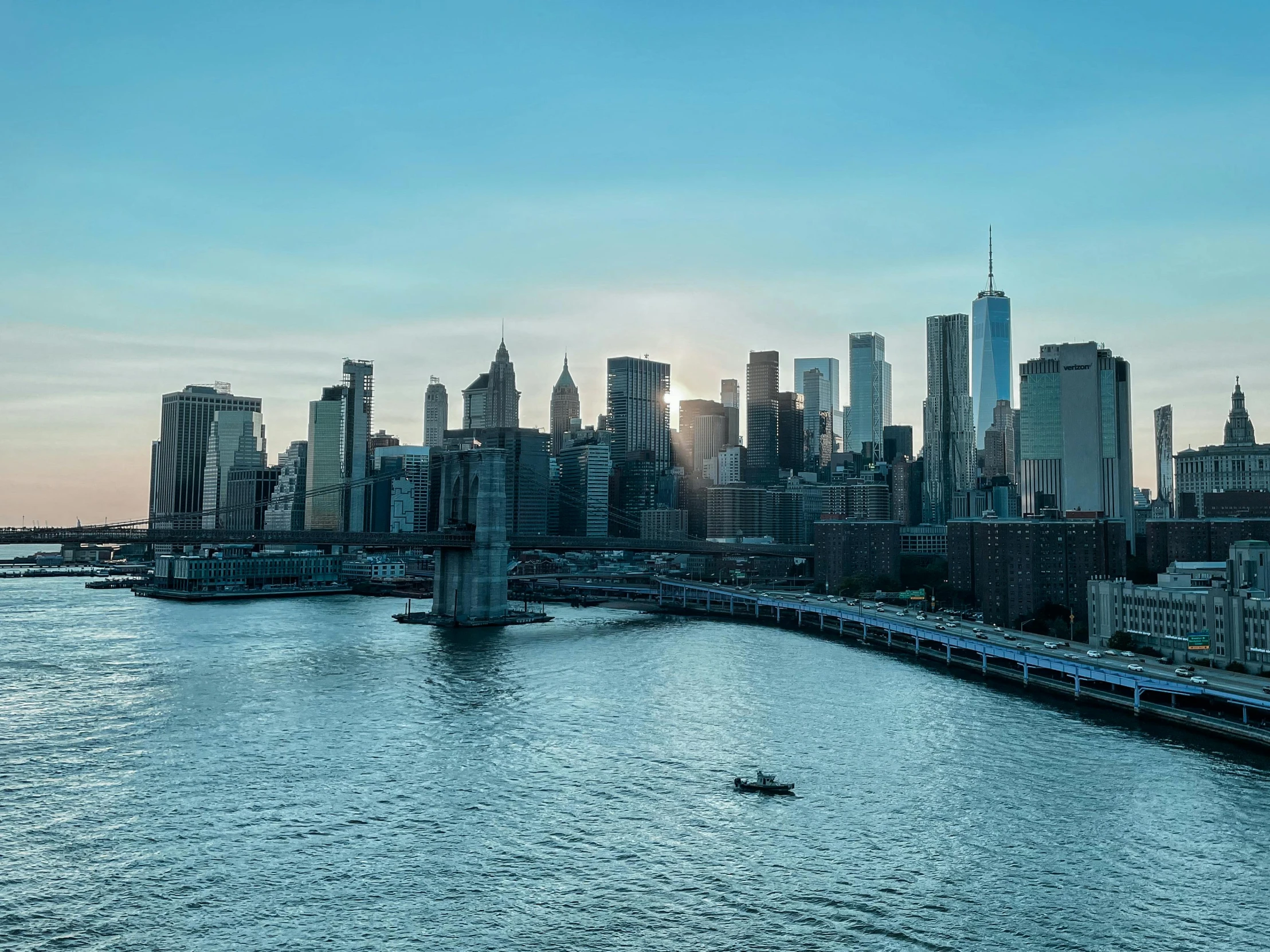 a city skyline with a river and a ferry passing by