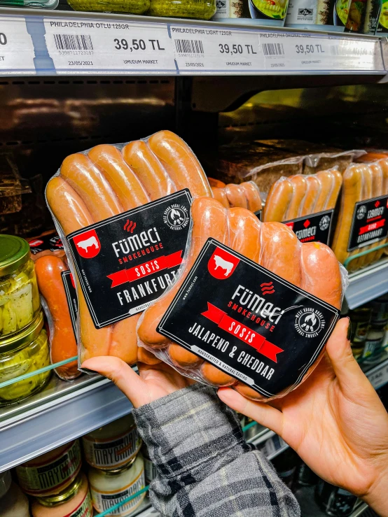 someone holding some meat next to another in a supermarket shelf