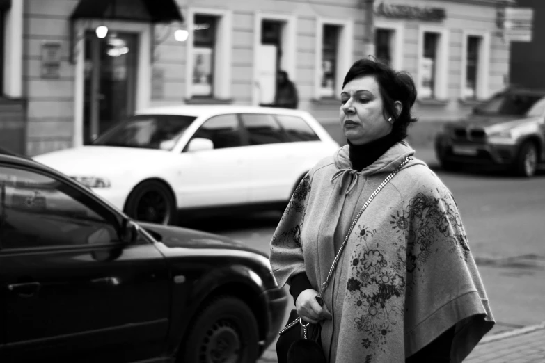 a woman in a shawl stands in the street