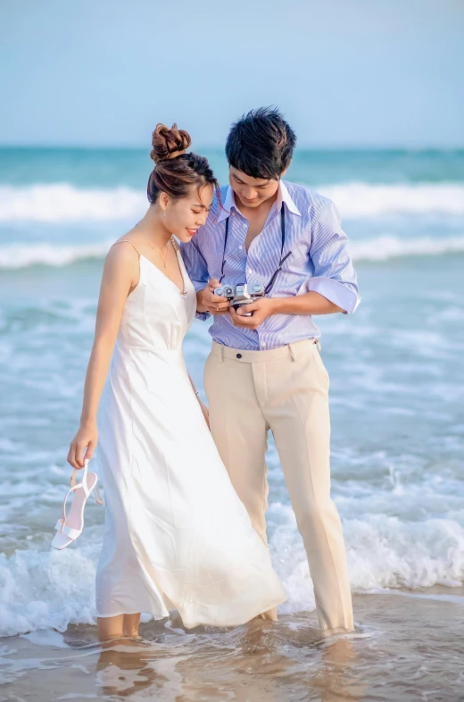 a young couple at the beach looking at their cell phones