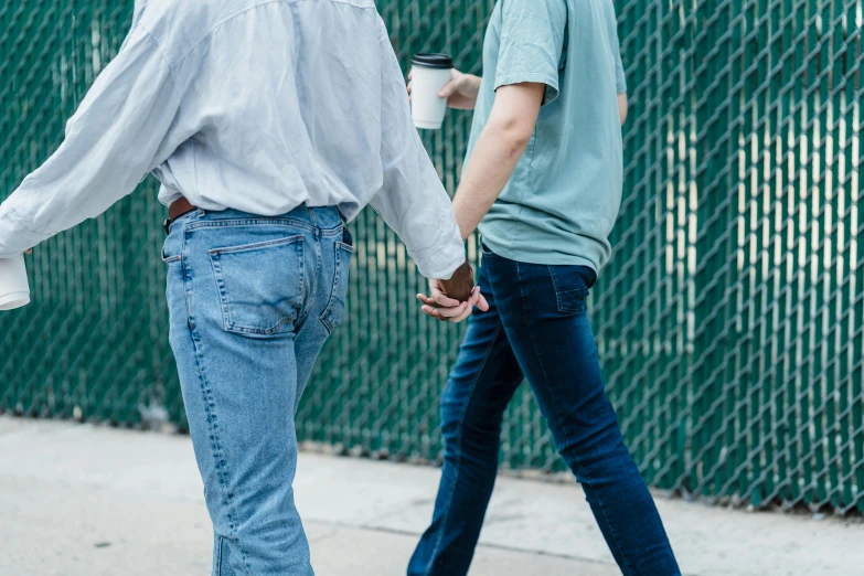 two people hold hands walking near the fence
