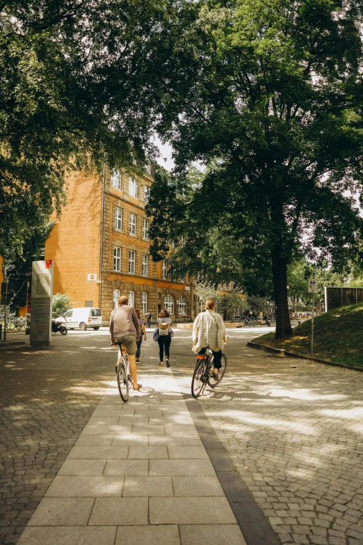 people are walking, biking and sitting around in the shade