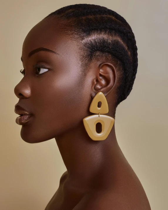 a woman wearing wooden earrings with two different shapes