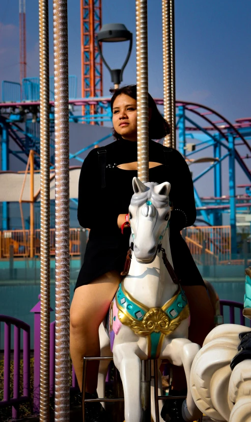 a woman riding on top of a white horse next to roller coaster